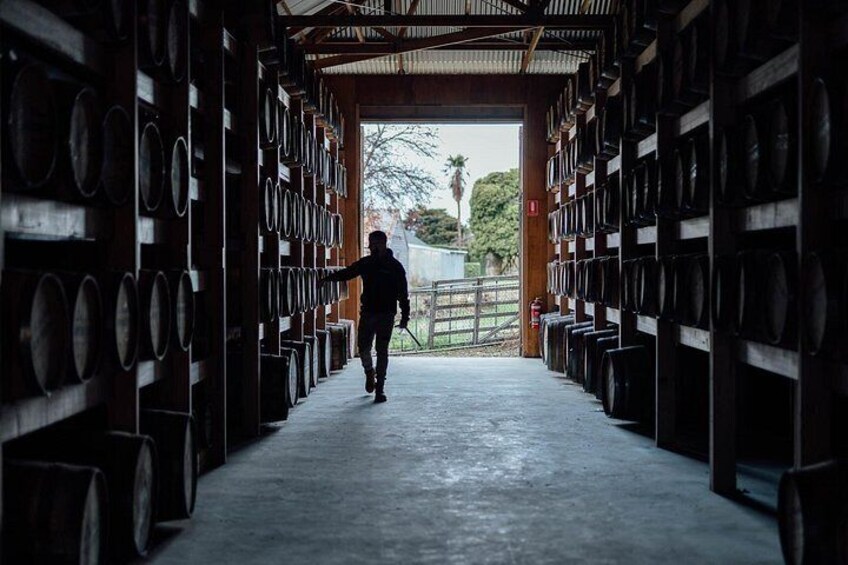 A person walking through a warehouse with rows of barrels. 2