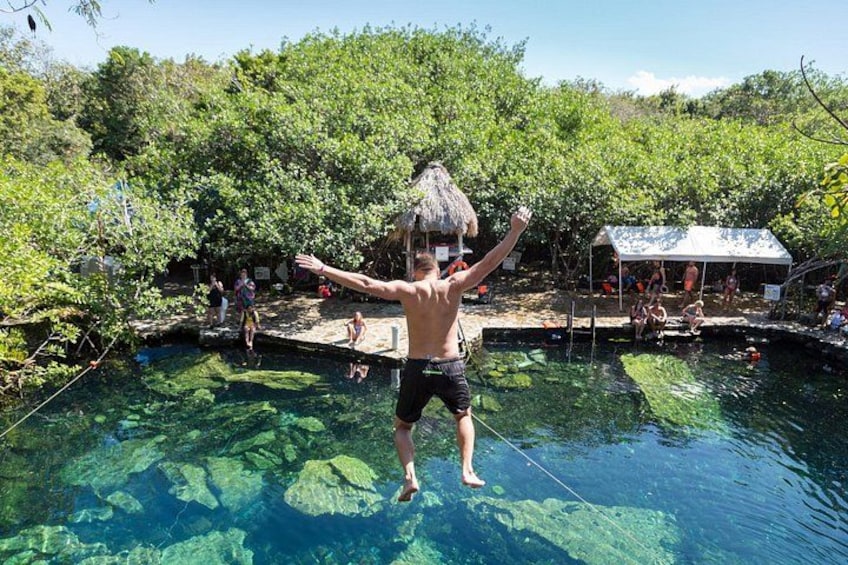 Una persona salta a una piscina cristalina rodeada de abundante vegetación. 1