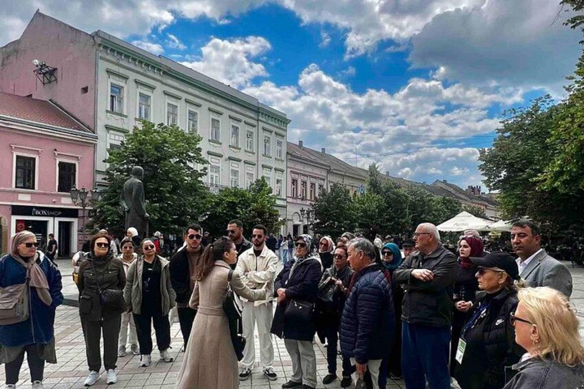 A group of people gathered in an outdoor public space with buildings in the background. 4