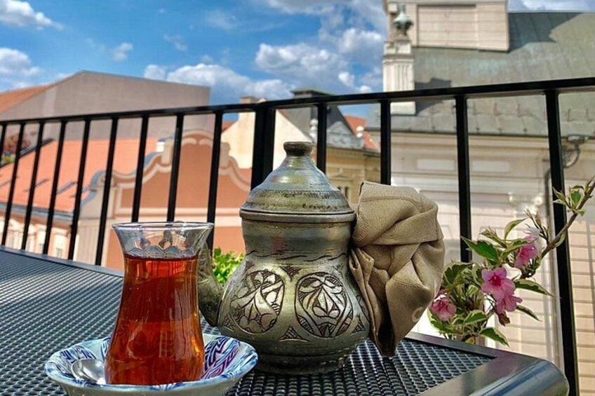 A table with a glass of tea, a metal container, and a cloth on a balcony. 2