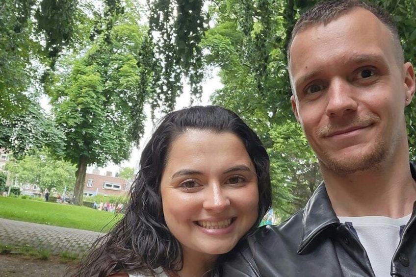 Deux personnes dans un parc, avec des arbres et un bâtiment en arrière-plan. 2