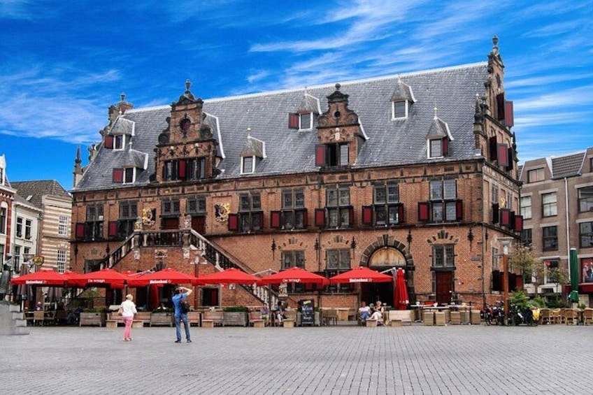 Un bâtiment historique doté d’auvents rouges et bordant une place pavée. 1