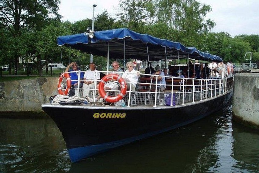 Un bote llamado 'GORING' con pasajeros y boyas salvavidas, amarrado en un canal. 1
