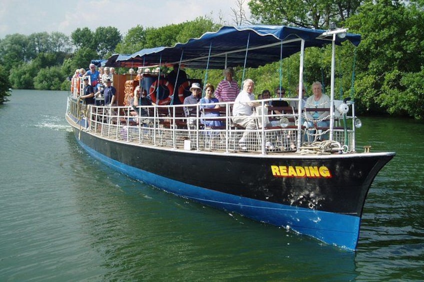Un barco llamado 'READING' con pasajeros, navegando por un río rodeado de vegetación. 5