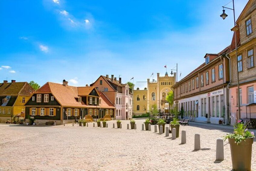 Una plaza adoquinada con edificios históricos, una torre y cielo azul despejado. 2