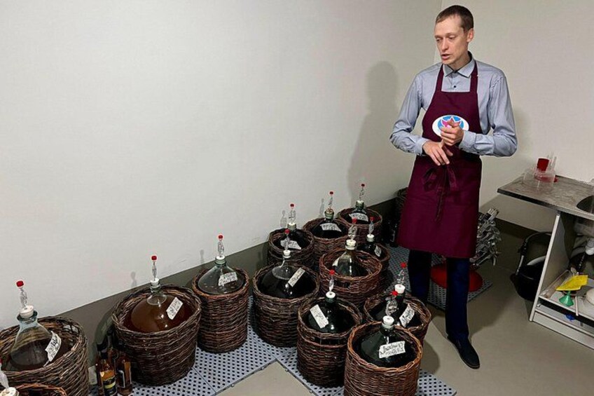Una persona en una cocina con varias cestas de mimbre que contienen botellas, algunas sobre un tapete y otras en un estante. 5
