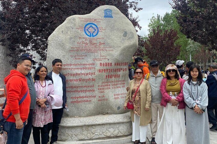 A group of people standing in front of a large stone monument with inscriptions. 2