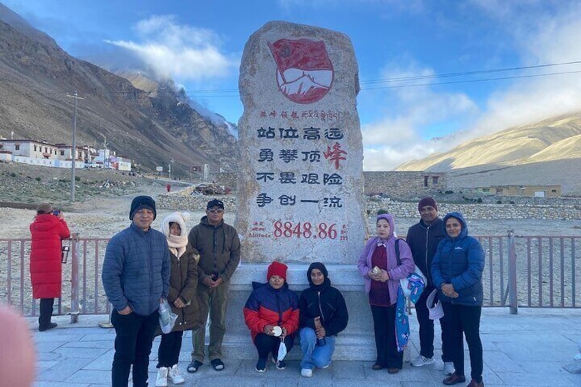 A group of people posing in front of a large stone monument with inscriptions. 4