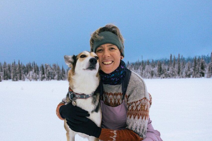 A person holding a dog in a snowy landscape with trees in the background. 2
