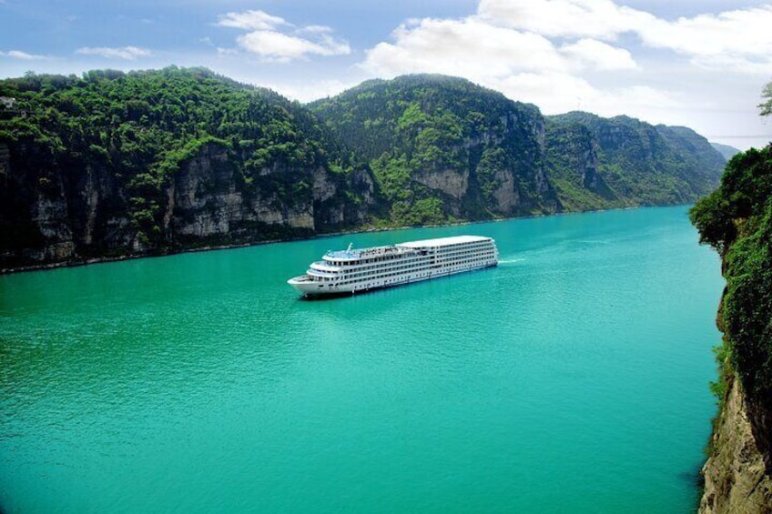 A cruise ship on turquoise waters surrounded by lush green cliffs. 2