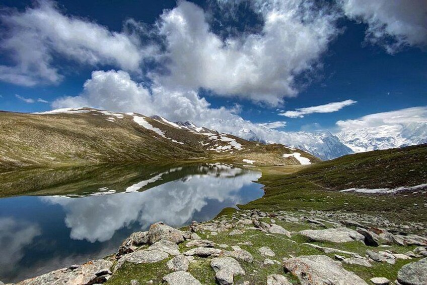 Un paisaje montañoso con un lago que refleja el cielo y las nubes. 3