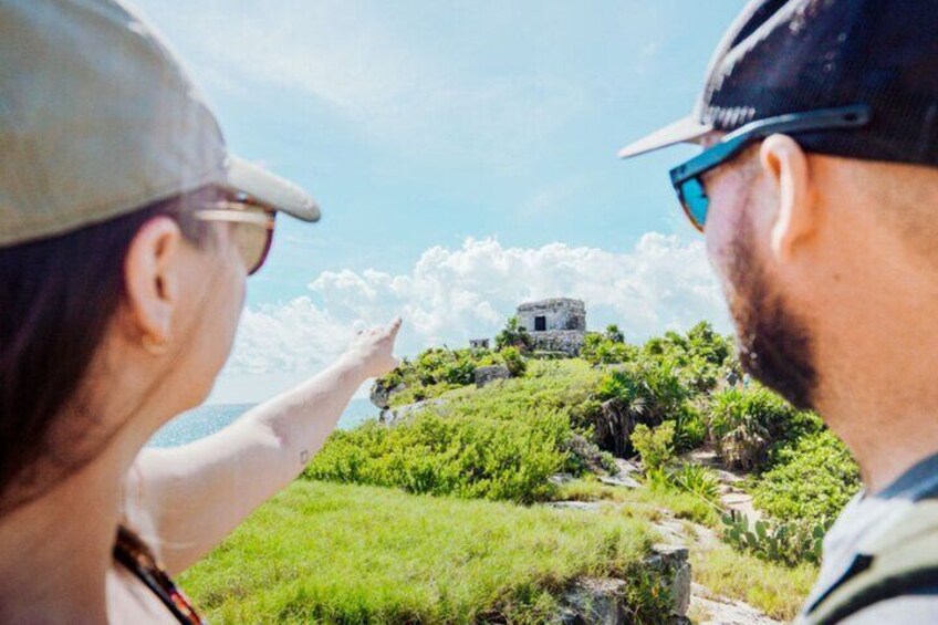 Two people looking at an ancient ruin on a grassy hill. 5