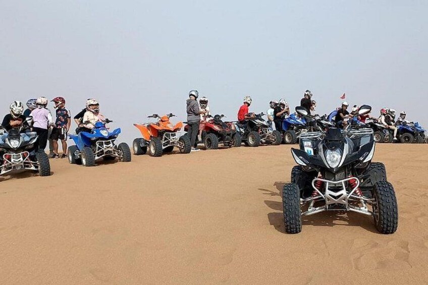 A group of people on quad bikes in a desert. 2