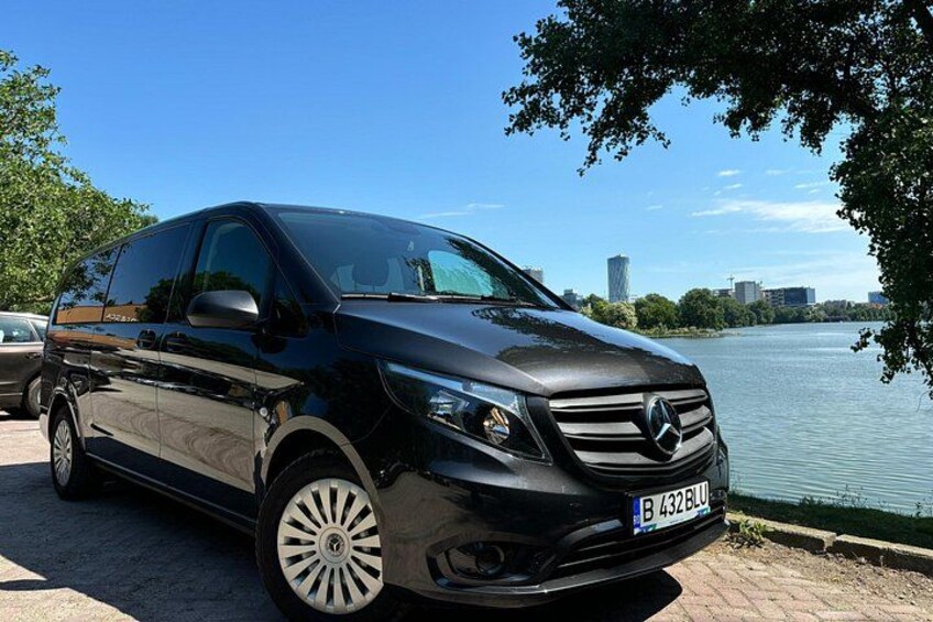 Ein schwarzer Mercedes-Benz C-Klasse Sedan parkt am Ufer, im Hintergrund ist eine Stadtlandschaft zu sehen. 4