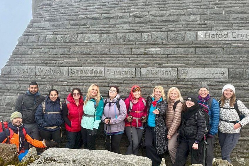 A group of people standing in front of a stone monument with inscriptions. 2