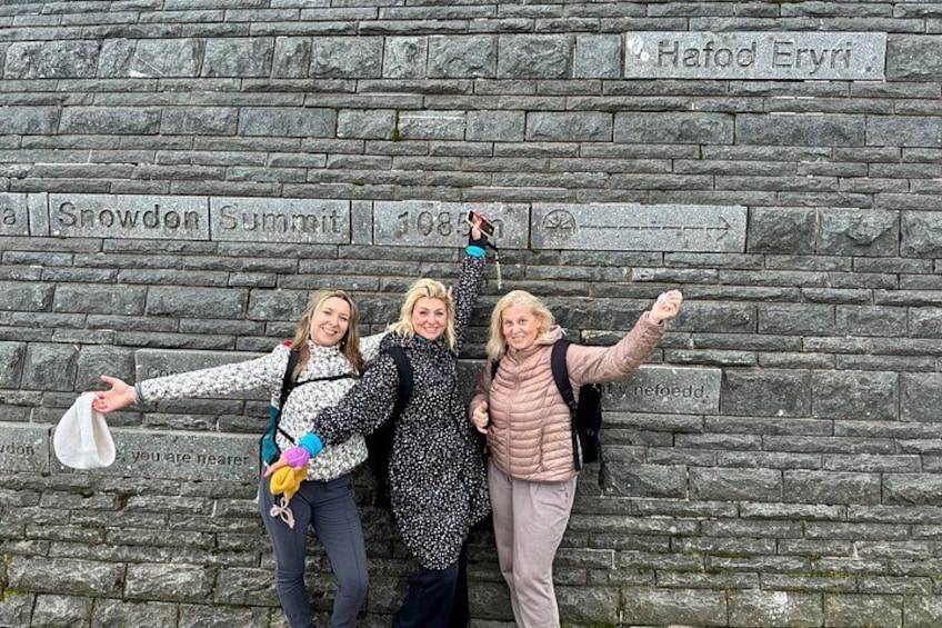 Three people standing in front of a stone wall with inscriptions. 3