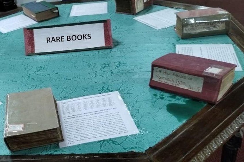 A table with a sign reading 'RARE BOOKS' and several books and papers on it. 2