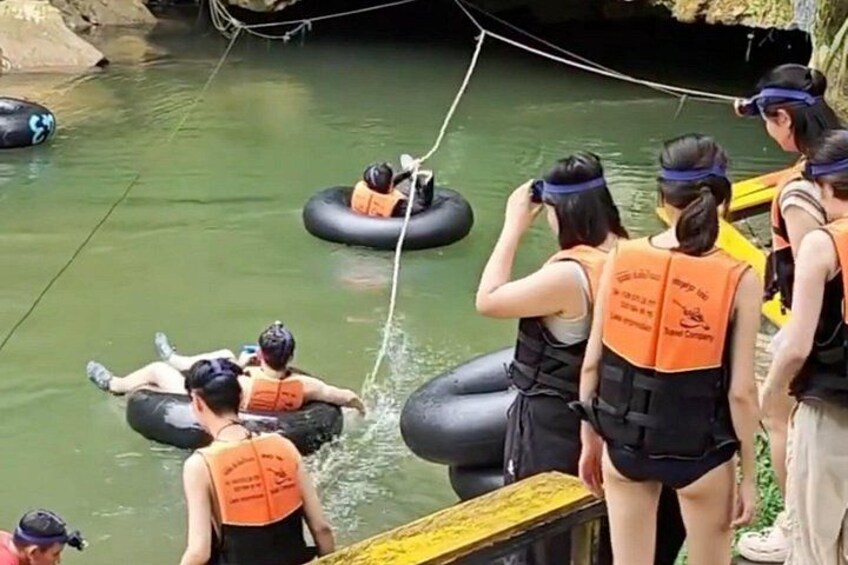 People floating on water tubes, wearing life jackets, and a yellow boat in a river. 4