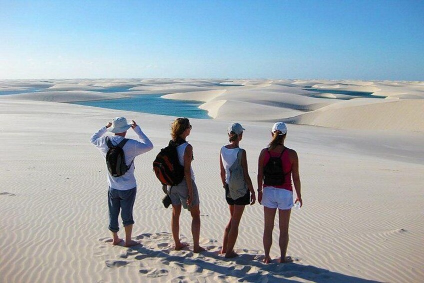 Quattro persone in piedi sulle dune sabbiose con vista su un'area d'acqua. 2