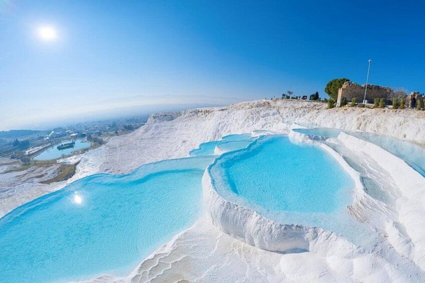 Terraced pools of clear water, a clear sky, and a distant landscape. 2