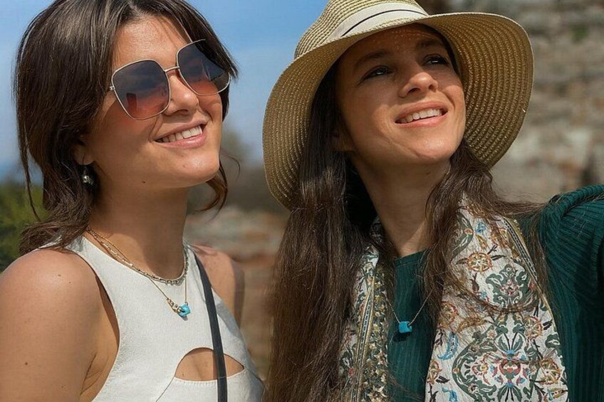 Two people outdoors, one wearing a hat and the other in a sleeveless top. 1