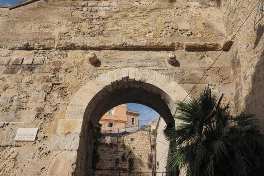 Una estructura de piedra con arco y una palmera en primer plano. 2
