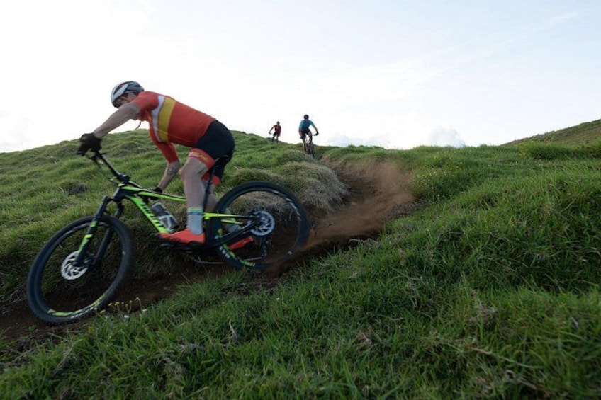 Una persona montando una bicicleta de montaña en una colina cubierta de hierba. 3