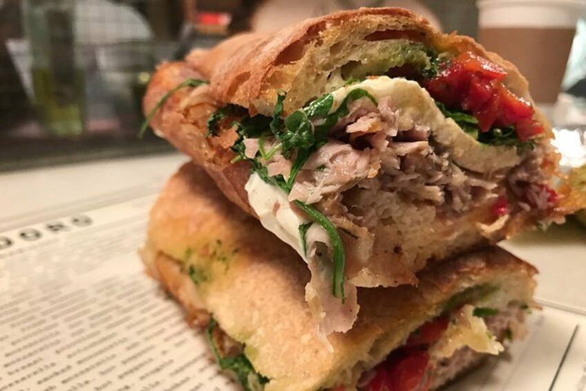 Un sándwich sobre un plato con ingredientes visibles como lechuga, tomate y posiblemente pollo. 3
