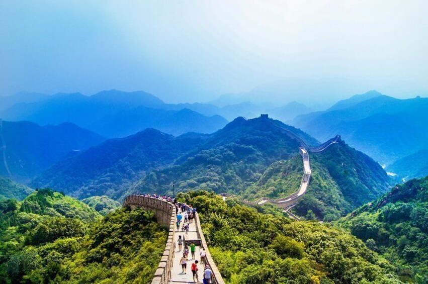 The Great Wall of China winding through lush green mountains. 1