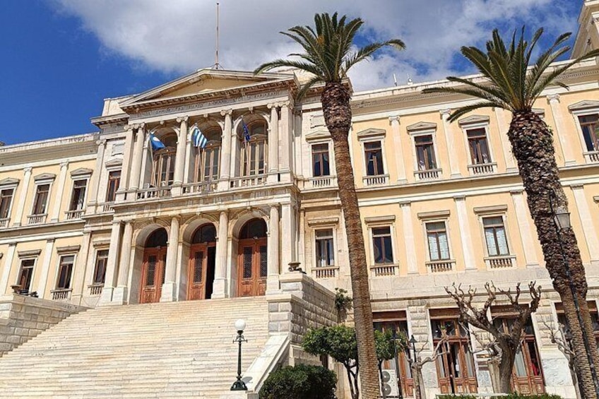 A classical building with columns, a grand staircase, and palm trees. 5