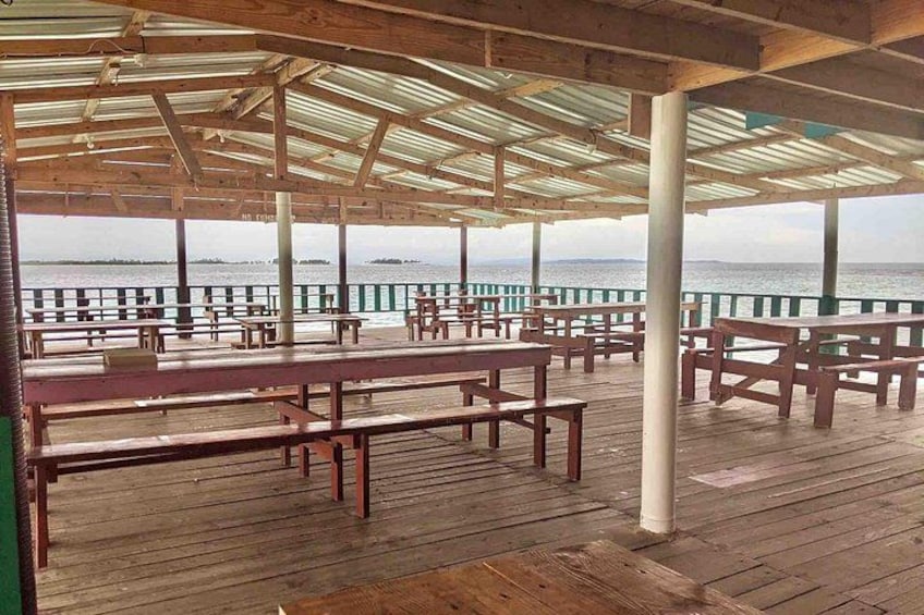 An empty wooden deck with picnic tables and a view of the water. 4