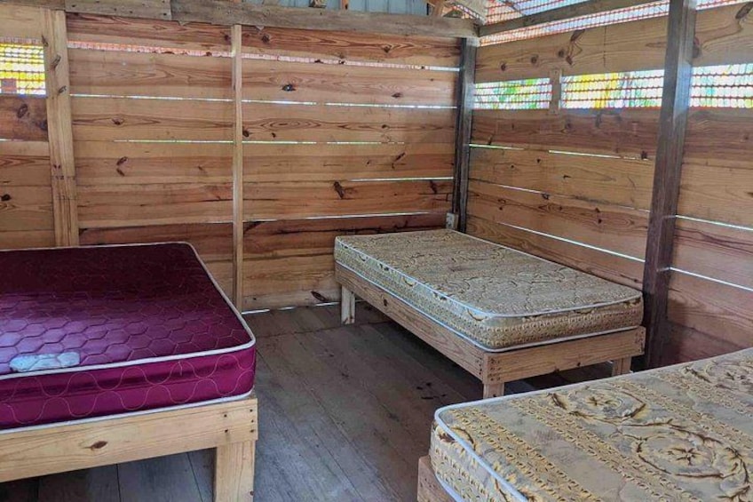 A wooden cabin interior with two beds and a small table. 3