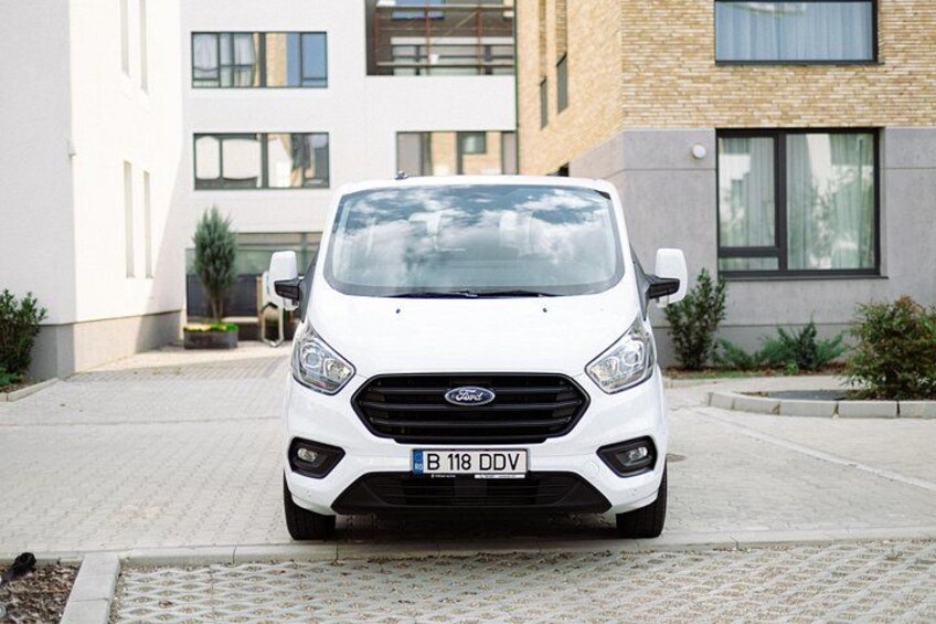 Un coche Ford blanco estacionado frente a un edificio moderno con fachada de ladrillo. 2