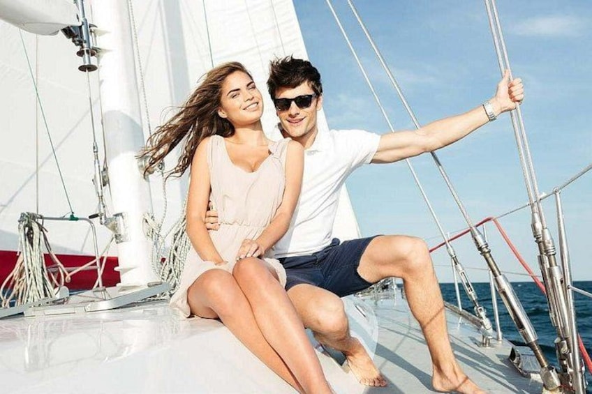 Una pareja en un velero bajo un cielo despejado y un mar tranquilo. 3