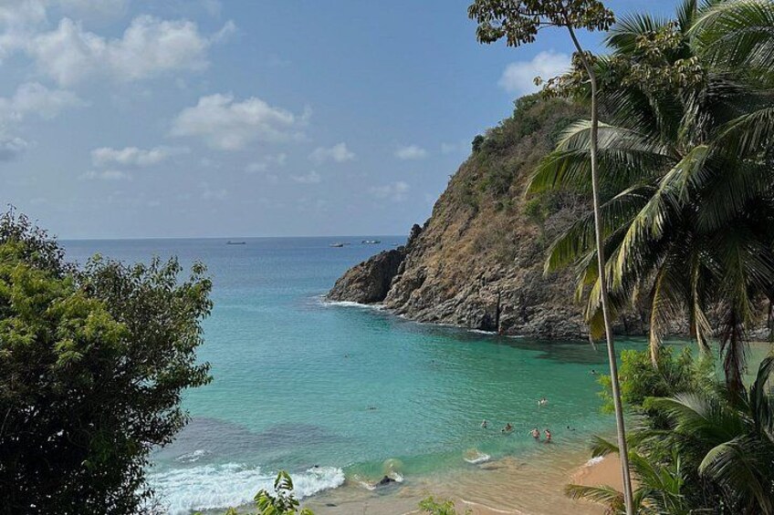 A coastal landscape with clear turquoise waters, a sandy beach, and a rocky cliff. 4