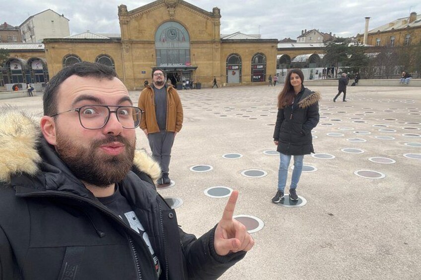 Una persona señala un diseño circular en el suelo, con un edificio al fondo. 5