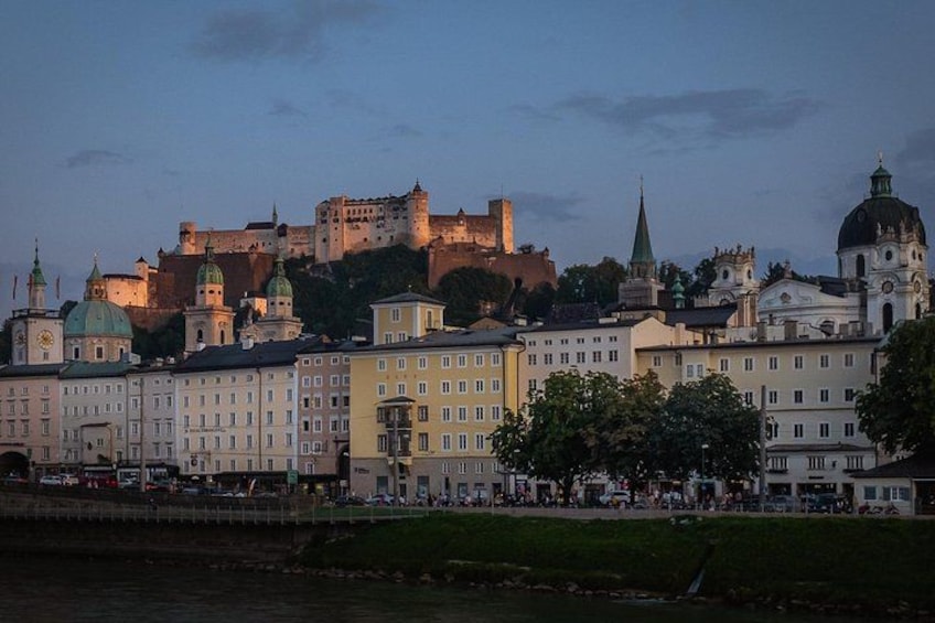 A cityscape with historic buildings, a castle, and a river. 1