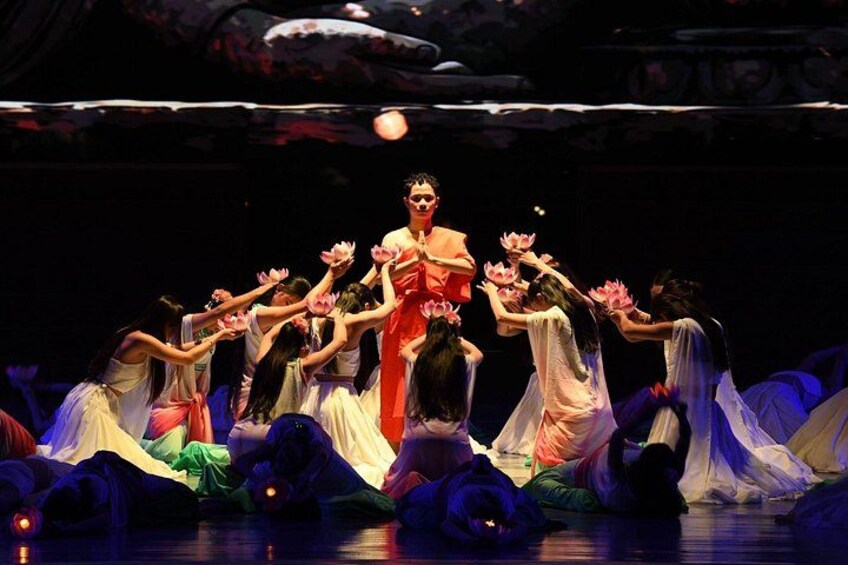 Un grupo de bailarines con trajes blancos y rosas actuando sobre un escenario con fondo oscuro. 2