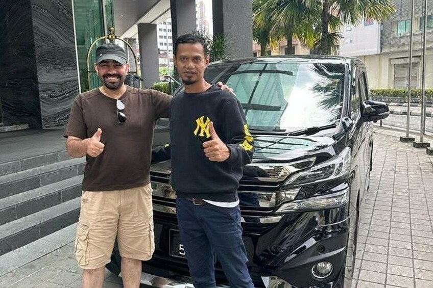 Two people standing next to a black SUV with a yellow logo on the hood. 5