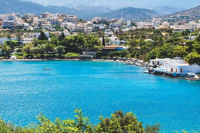A coastal town with buildings, a clear blue sea, and a boat. 5