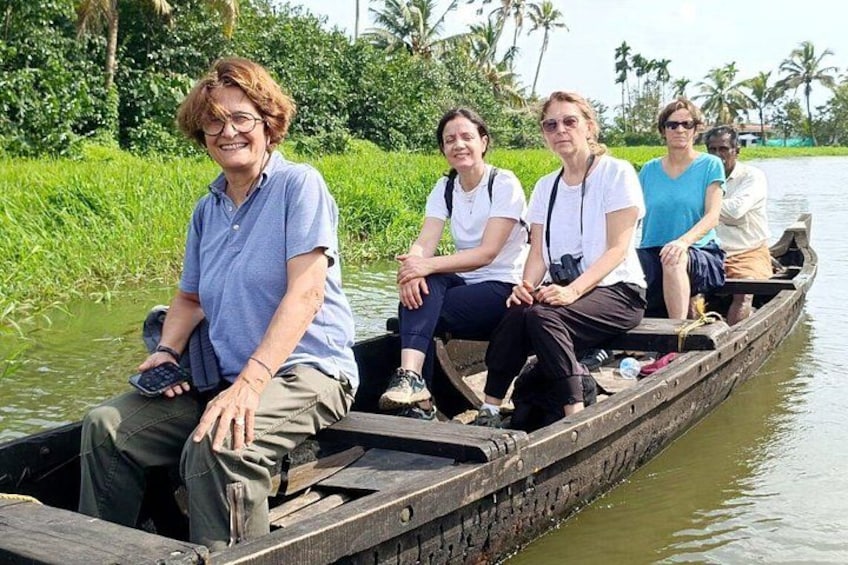 A group of people on a wooden boat in a river surrounded by greenery. 1