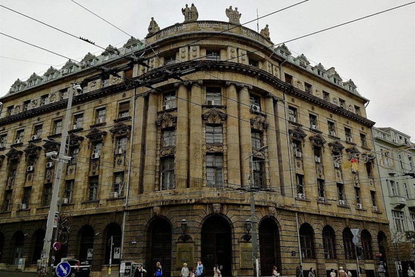 A historic building with ornate architecture, large arched windows, and a curved facade. 3