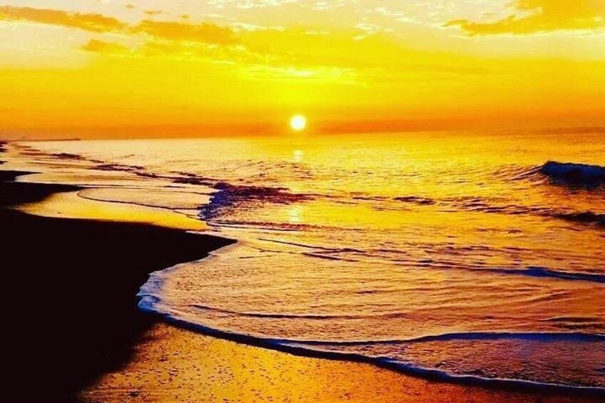 Atardecer sobre una playa con olas y cielo despejado. 2