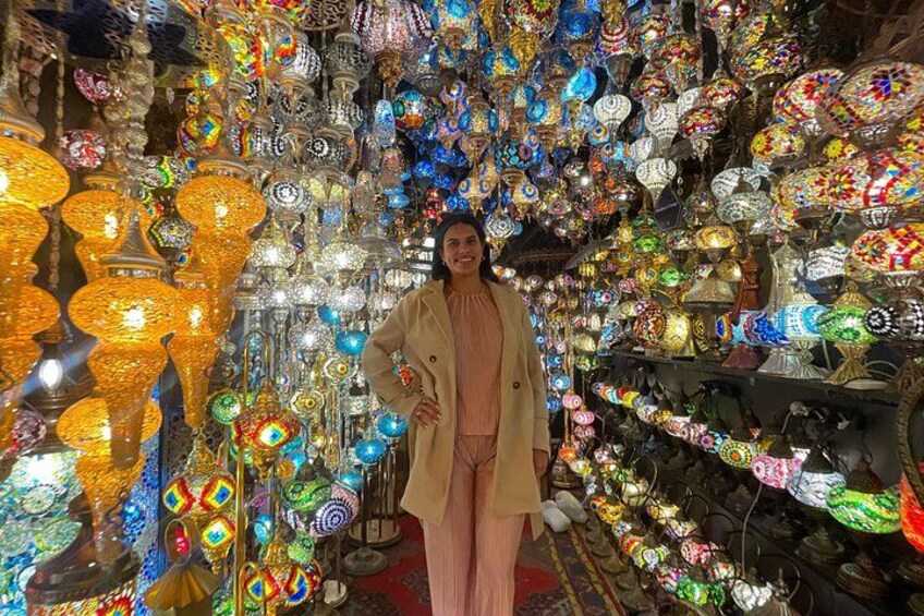 Une personne se tient dans un magasin rempli d’objets en verre aux couleurs vives. 1