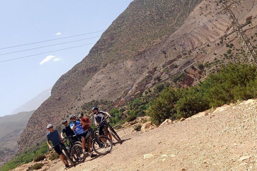 A group of cyclists on a dirt path with a mountainous backdrop. 4