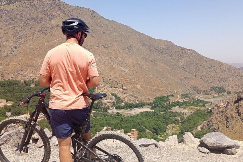 A person standing next to a bicycle overlooking a valley with mountains in the background. 2