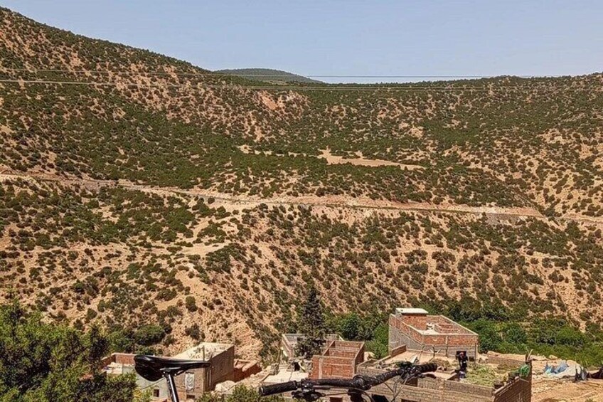 A hilly landscape with sparse vegetation and a few buildings at the base. 3