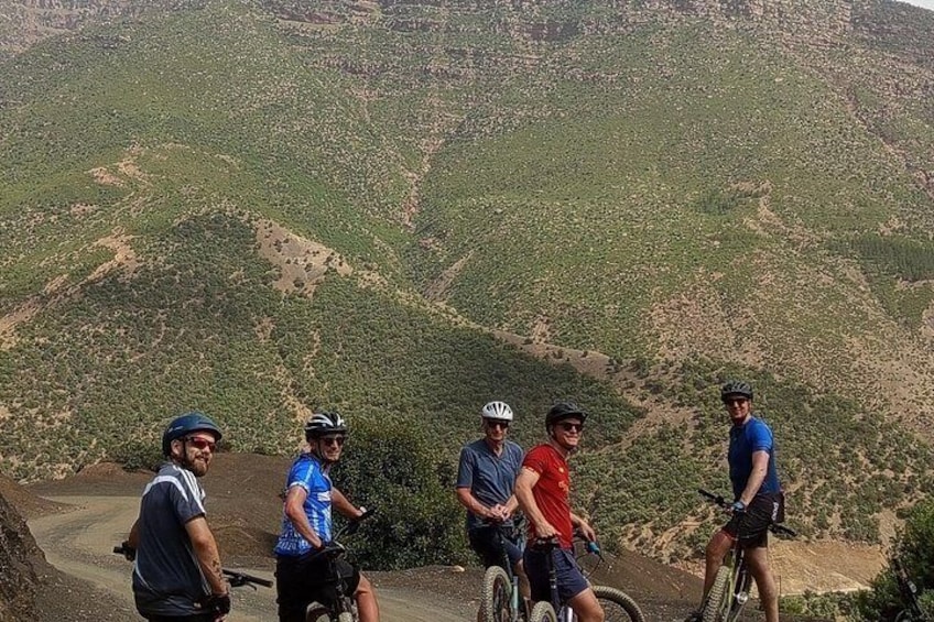 A group of cyclists on a mountain road with a hilly landscape in the background. 5