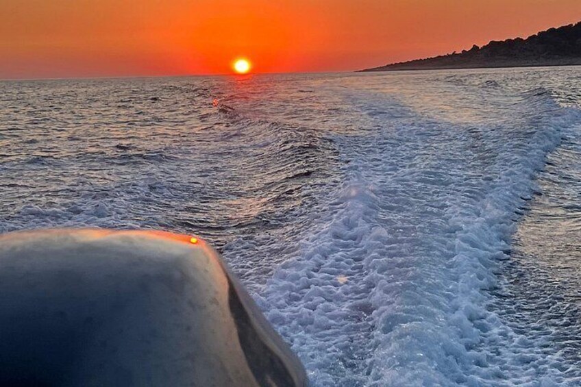 A boat's wake in the ocean with a sunset in the background. 2