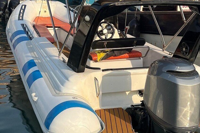 A motorboat with a steering wheel, a canopy, and a metal container. 3